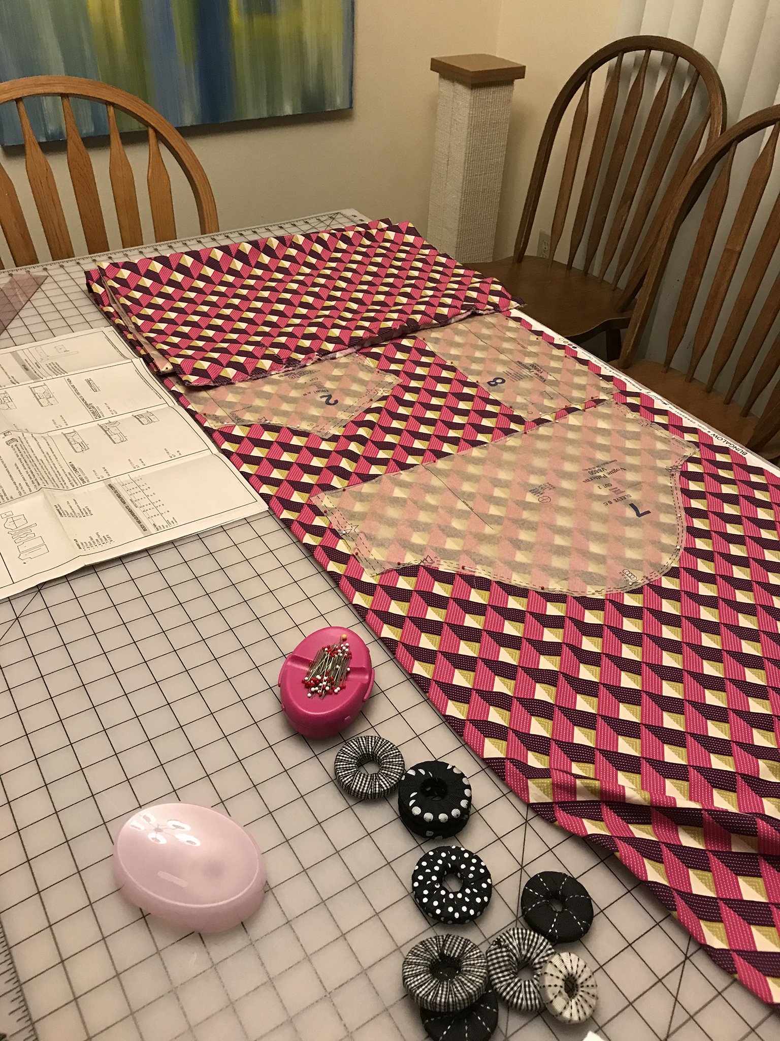 Laying out pattern pieces on pink geometric print fabric.