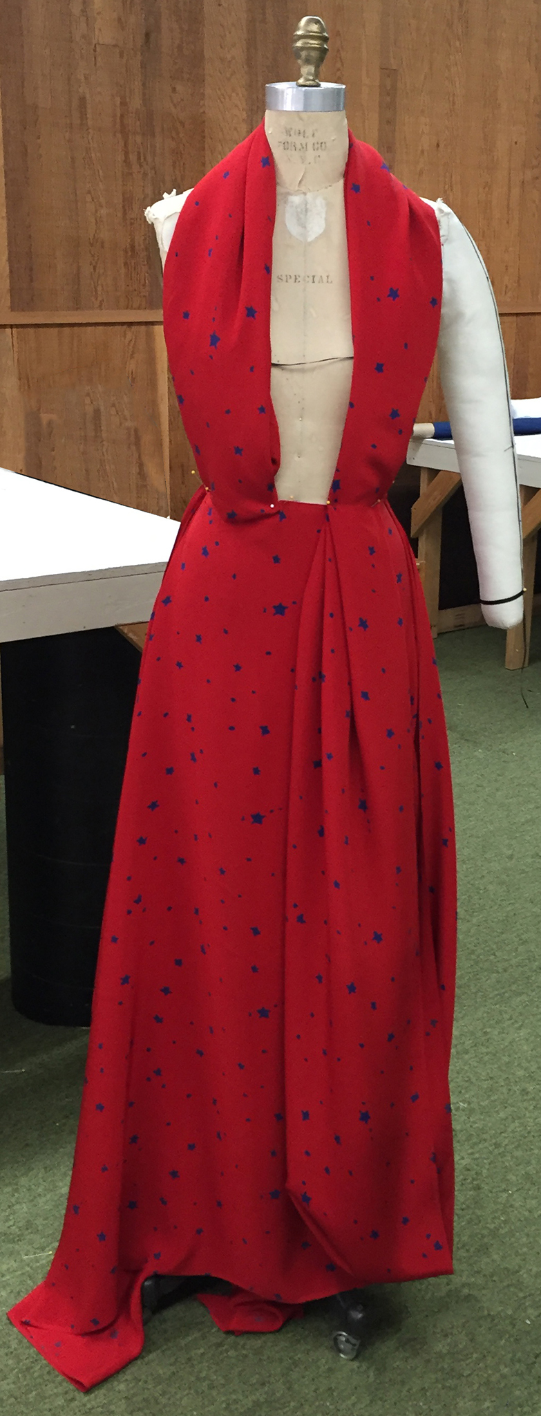 Red silk crepe with blue stars draped over a dress form.