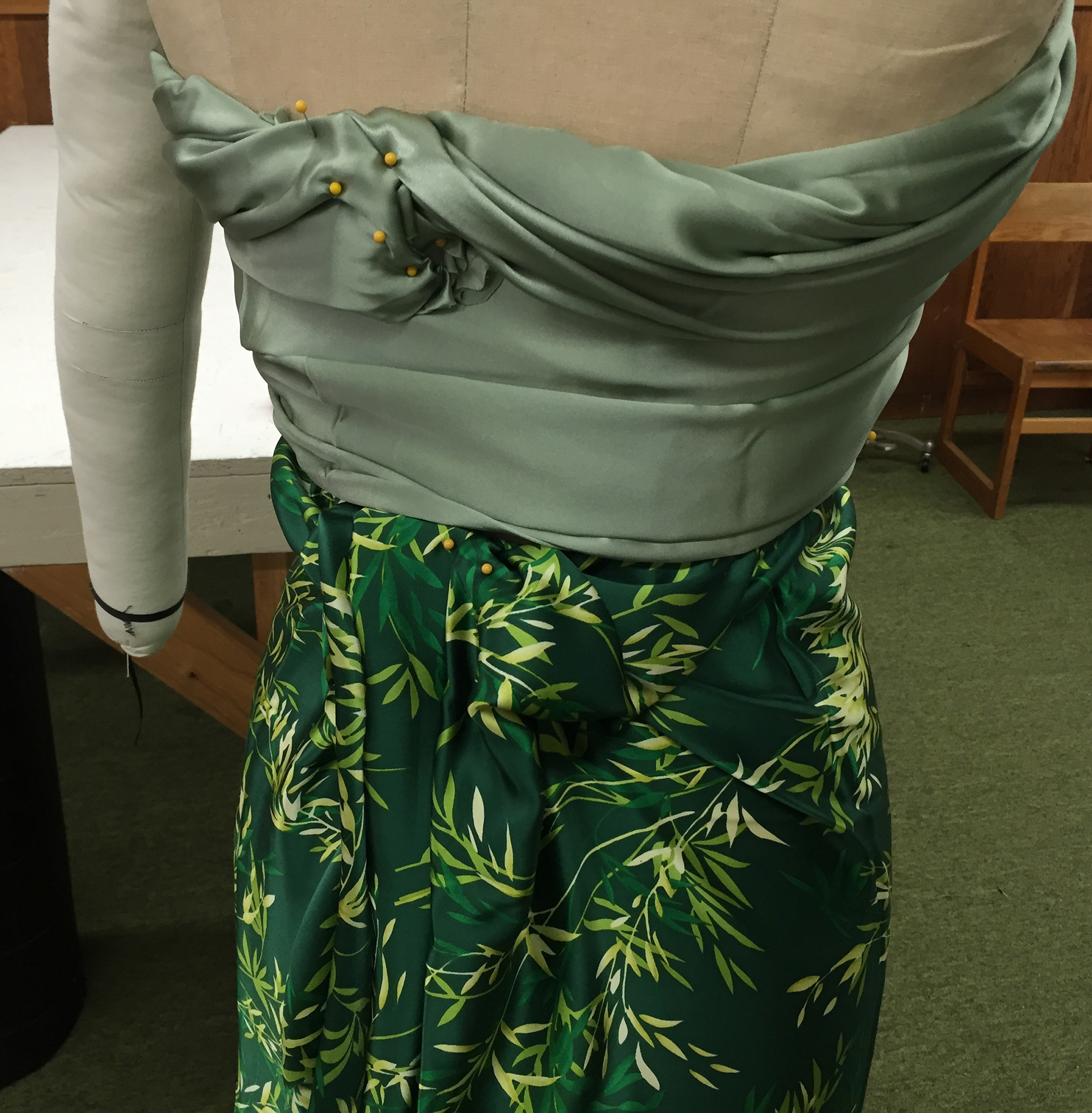 Two different bolts of green charmeuse fabric draped over a dress form.