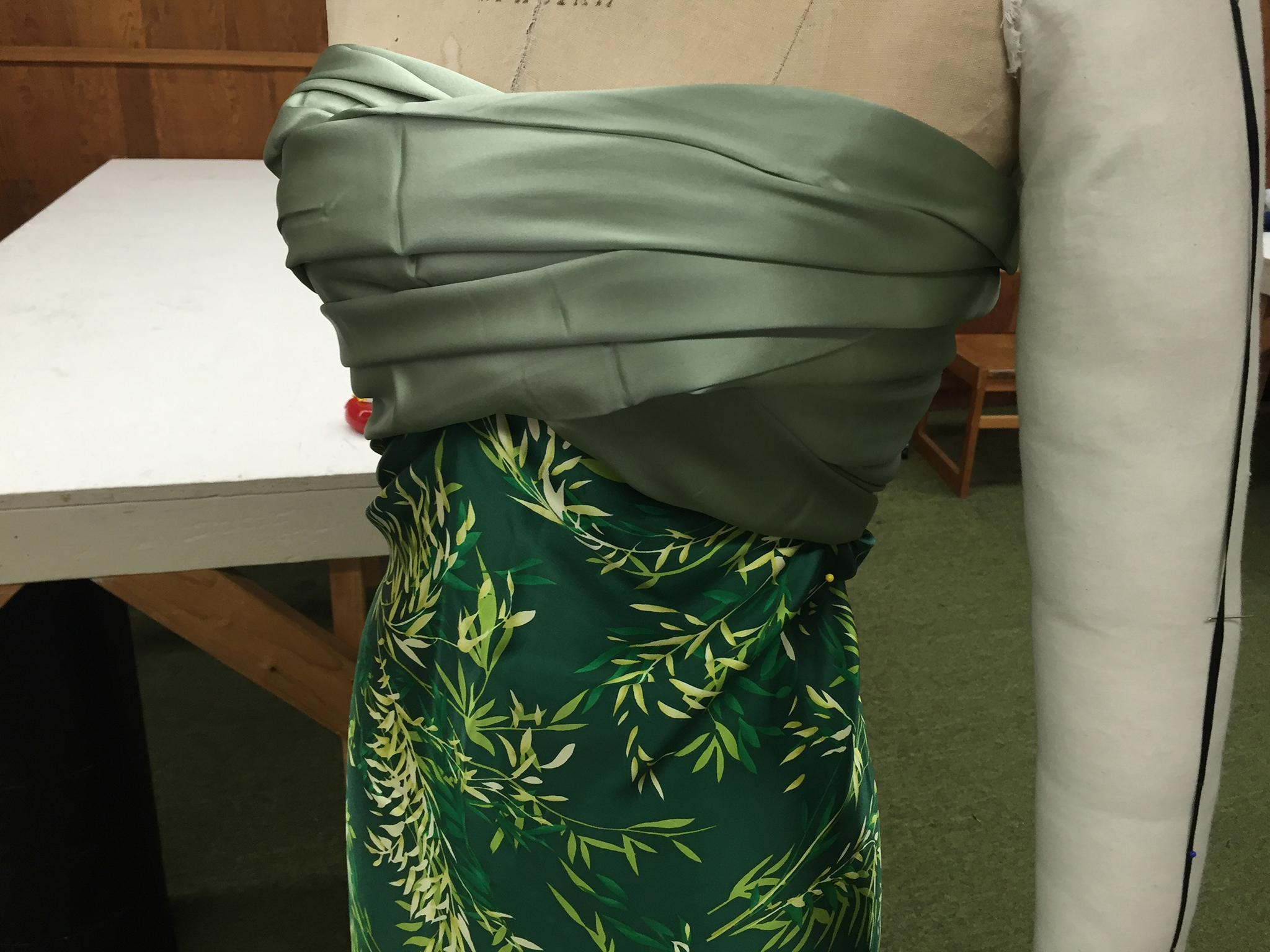 Two different bolts of green charmeuse fabric draped over a dress form.