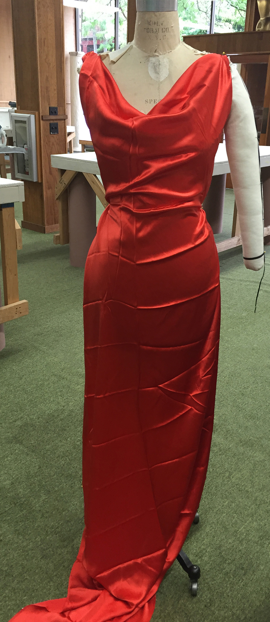 Red silk satin draped over a dress form.