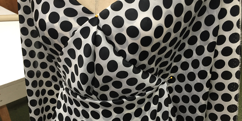 The front bodice of a draped dress with black polka dots on white silk organza.